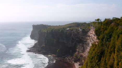 Antena-De-Los-Famosos-Acantilados-De-Piedra-Caliza-De-Uluwatu-Mientras-Las-Olas-Chocan-Contra-La-Playa-Rocosa-Debajo