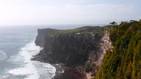 aerial of the famous limestone uluwatu cliffs as waves crash against the rocky beach below