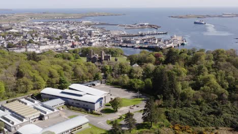 Drohnenaufnahme-Von-Stornoway-Mit-Einer-Passagierfähre,-Die-Im-Hintergrund-Den-Hafen-Verlässt