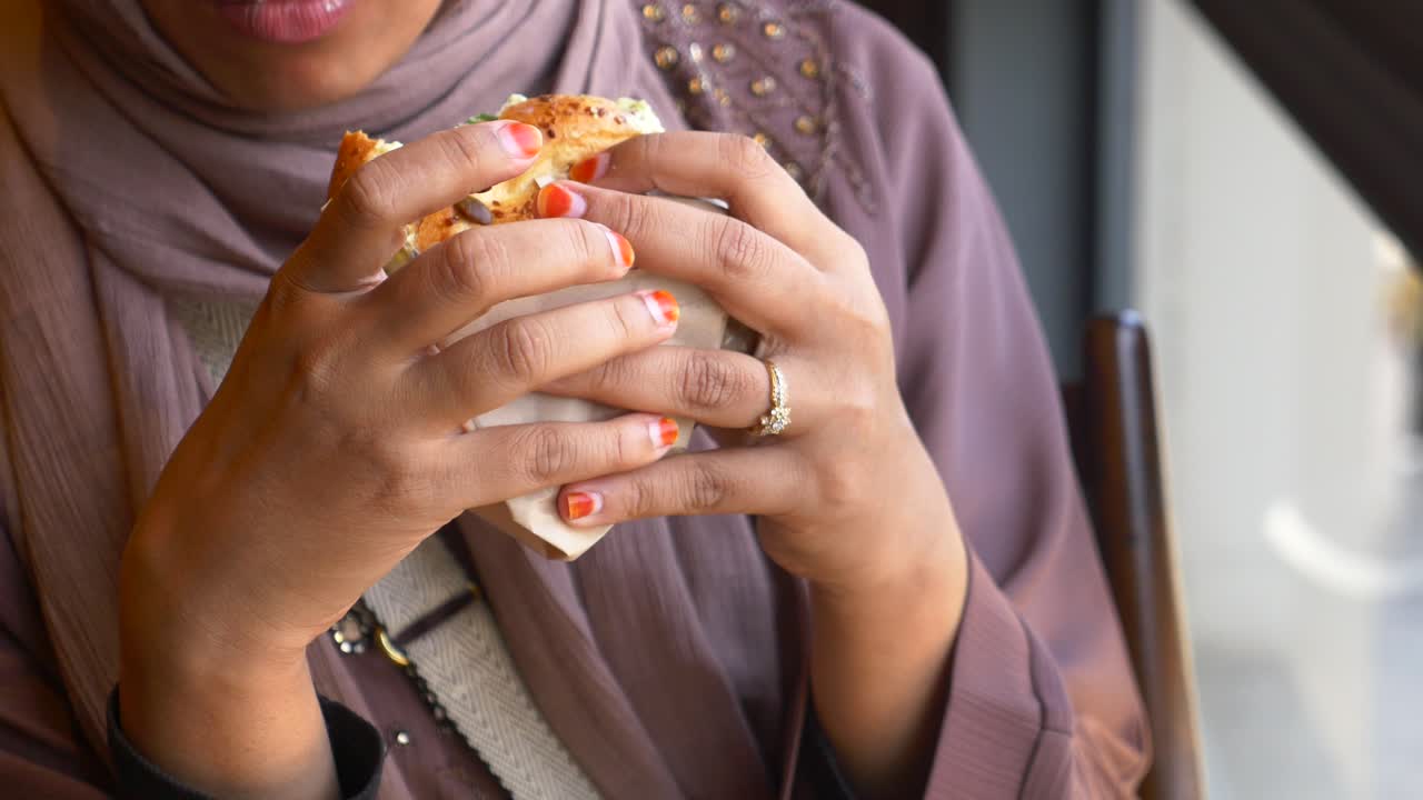 mujer comiendo un sándwich en un café