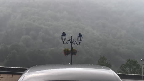 close up shot of rain and hail hitting a car during the day in the street of gavarnie gedre village in the wild pyrenees mountain national parc