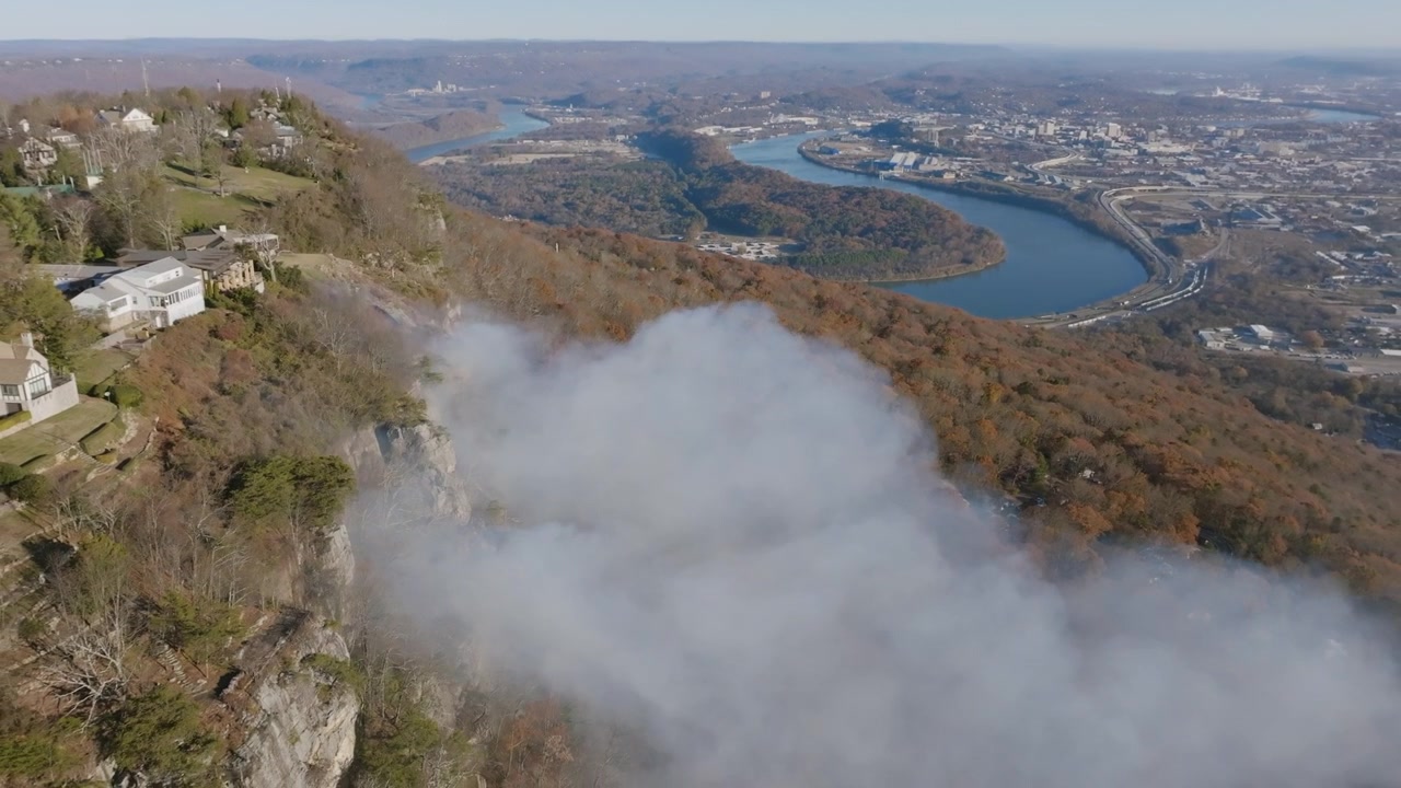 Riprese aeree che si allontanano dal fumo di un incendio boschivo che infuria intorno alle scogliere di Lookout Mountain con il fiume Tennessee e il centro di Chattanooga, TN, sullo sfondo