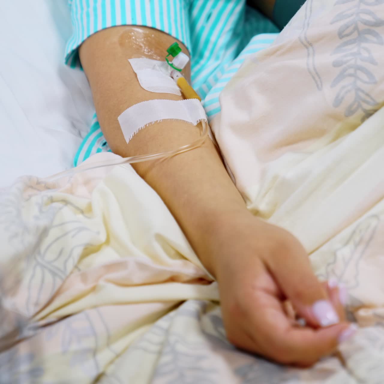 Mano femminile con cavo collegato proveniente da un conta gocce. Paziente sottoposto a infusione in un reparto ospedaliero. Primo piano