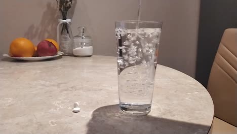 Clean-water-pouring-into-transparent-glass-on-the-table,-coffee-kitchen-background