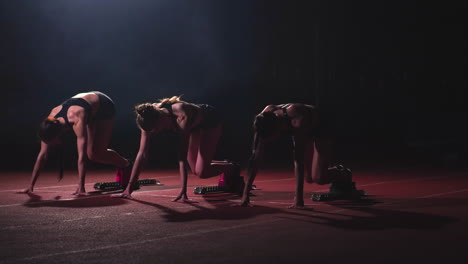 three girls in black clothes are in the starting pads to start the race in the competition.