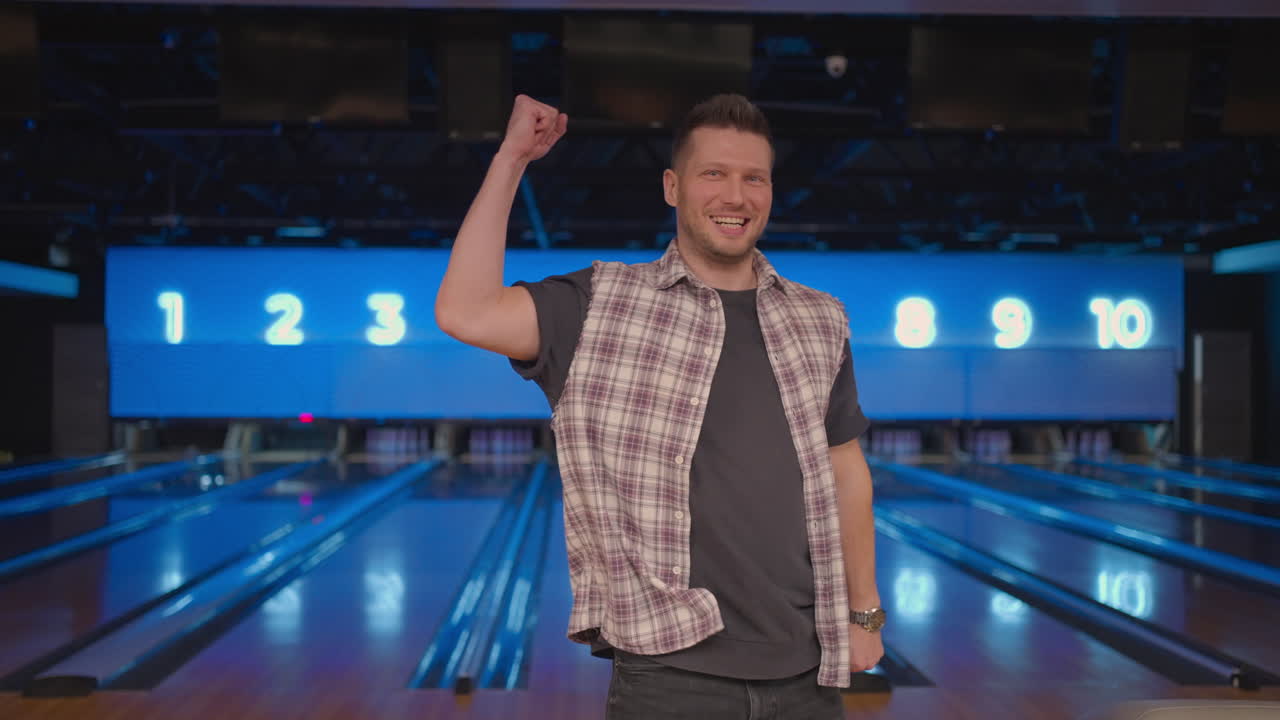 Caucasian man jumps joyfully looking into the camera celebrate the victory in slow motion. Throw in the bowling alley to make a shoot. Victory dance and jump with happiness.