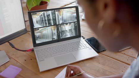 African-american-female-security-officer-watching-business-cctv-camera-views-on-laptop,-slow-motion