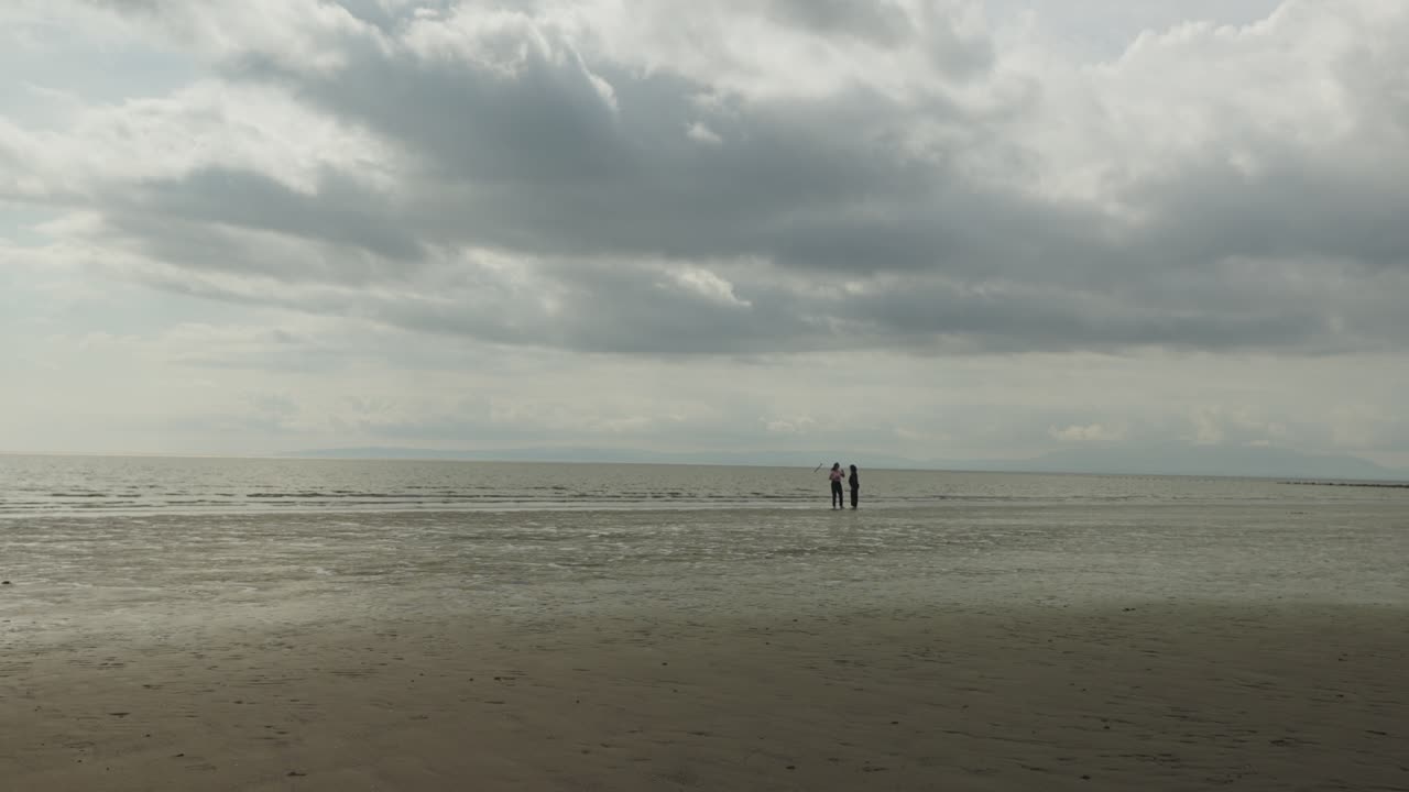 Cloudy sky, remote seaside location, people silhouettes, slow motion