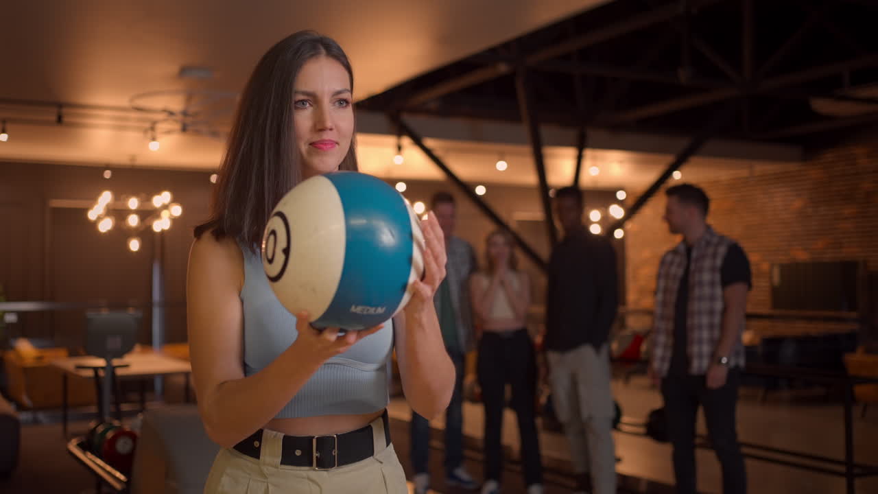 Multi ethnic Group of friends in a bowling club Portrait of a brunette woman throws a ball and knocks out a strike