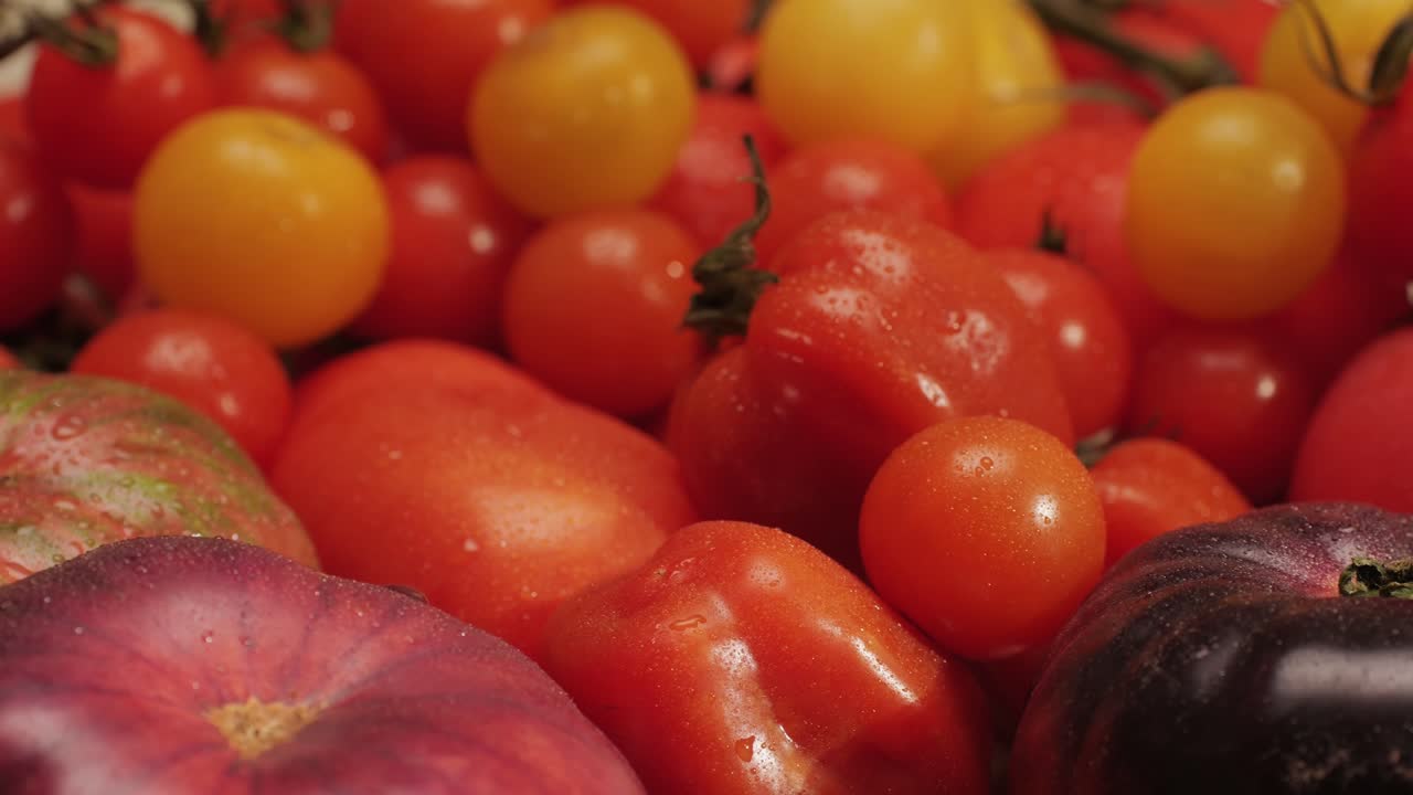 Colorful organic tomatoes. Mix tomatoes background, Several varieties of sliced tomatoes top view. Different assorted colorful tomatoes, heirloom, cherry, rose, beefsteak, cocktail, grape, purple.