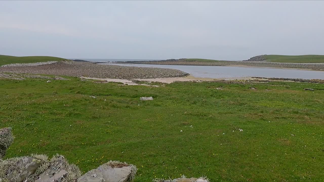 POV walking along rock wall on Scottish farm during cold day overlooking calm grey sea