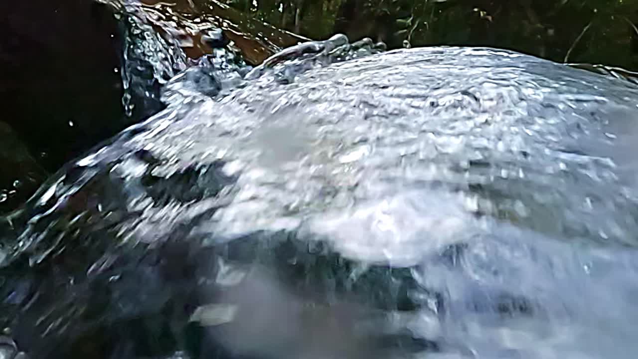 Fast moving water torrents, fluid sprays, creek rocks, slow motion scene
