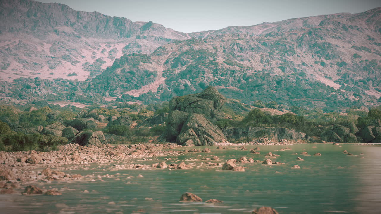 Şafakta, berrak sular ve arka planda dağlarla kayalık kıyı şeridi.