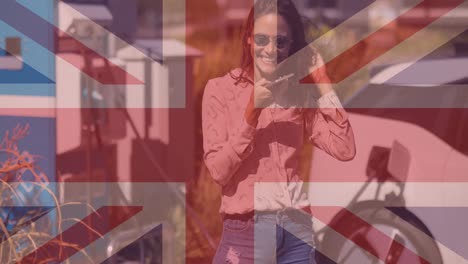 flag of great britain over woman using smartphone and charging electric car