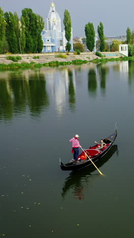 gondola floating along the river. woman enjoying time in a boat on the city background in the evening. aerial view. camera moves round. vertical video