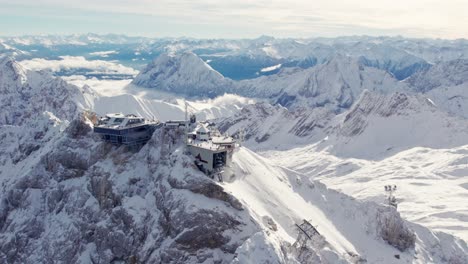 aerial of dramatic mountain summit with glacier in the background and a building on top