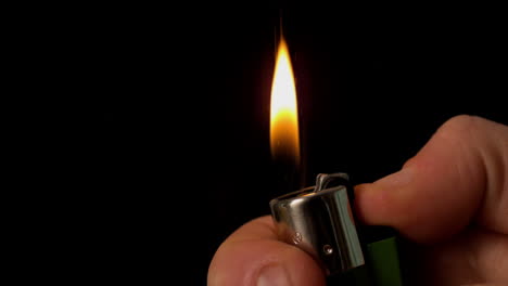 hand lighting a lighter on black background