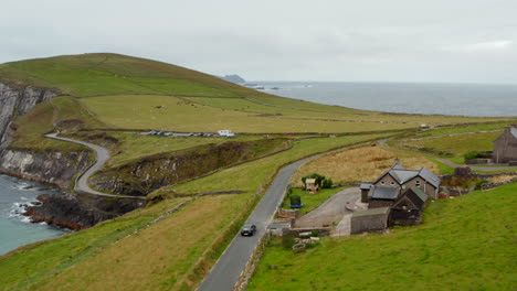 Car-driving-on-narrow-coastal-road-in-countryside.-Agricultural-landscape-with-green-meadows-and-pastures.-Ireland