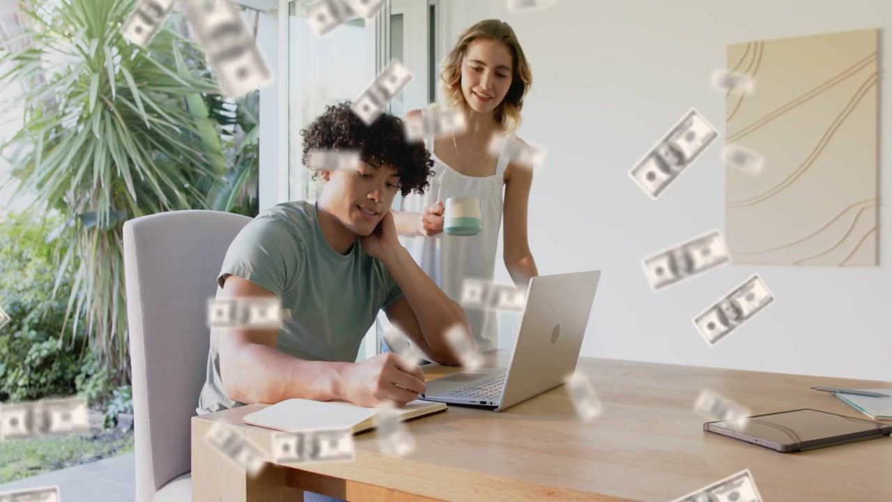 Man using laptop writing note as money bills falling obscuring faces, woman leaning planning budget