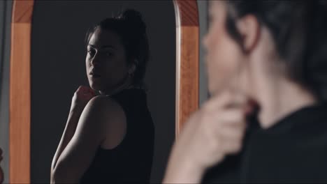 midshot of young woman dressing up in black in front of the mirror