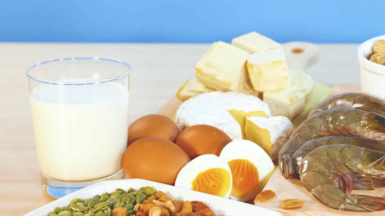 견과류, 달, 유제품을 포함한 다양한 단백질이 풍부한 음식이 자연 조명으로 파란색 배경에 표시됩니다.