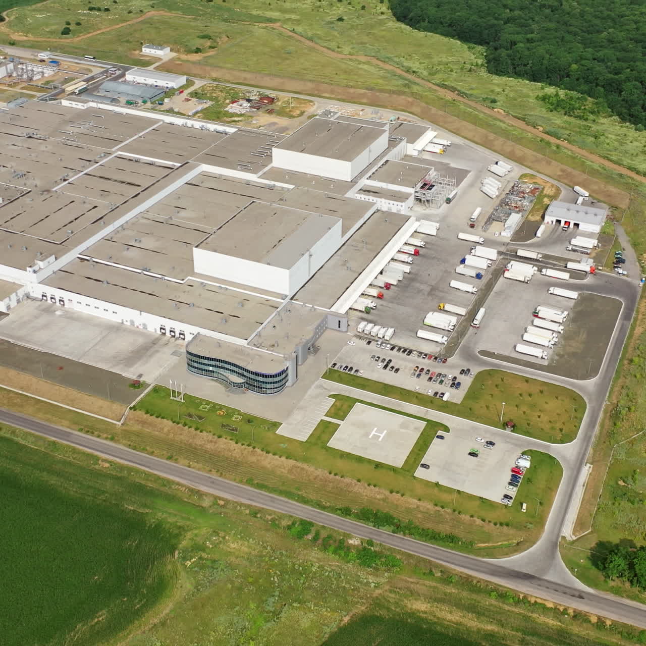 Modern exterior of industrial complex at daytime. Aerial view of manufacturing structure with parking for machinery outdoors.