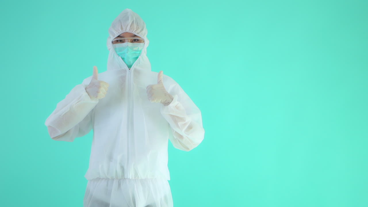 A woman Virologist medical worker showing a thumbs-up sign.Virologist in a white protective suit saying all is great. Global epidemic coronavirus