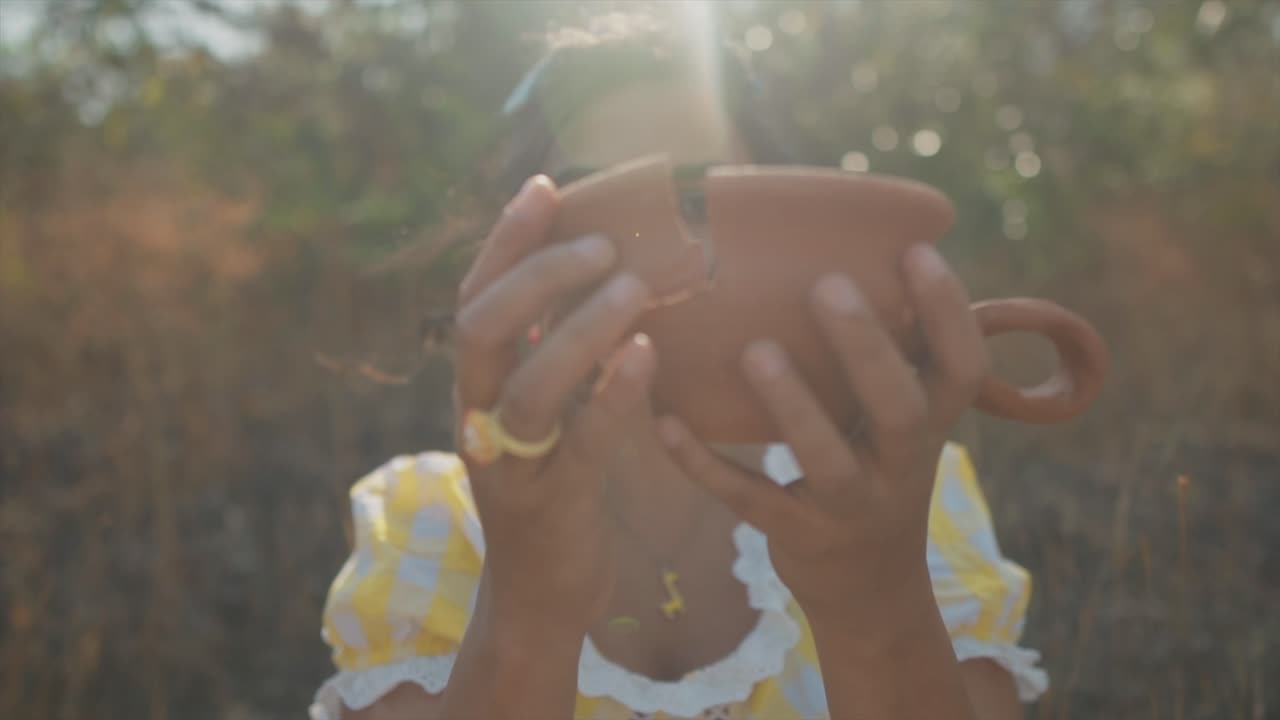 cámara lenta de ensueño se aleja mientras una hermosa mujer india sostiene un fragmento de cerámica roto y vuelve a juntar las piezas para crear una olla unificada