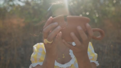 Dreamy-slow-motion-zoom-out-as-a-pretty-Indian-woman-holding-a-broken-shard-of-pottery-brings-the-pieces-back-together-to-create-a-unified-pot