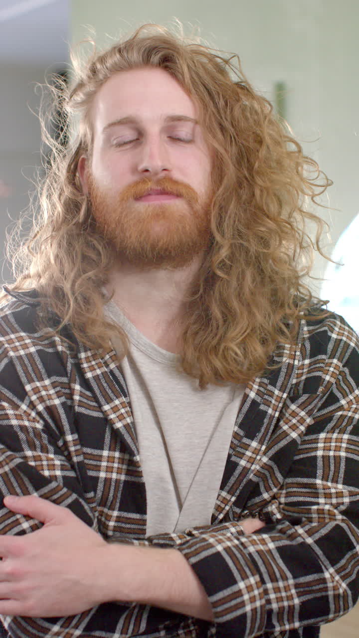 Vertical video of portait of caucasian male hairdresser smiling at hair salon, in slow motion