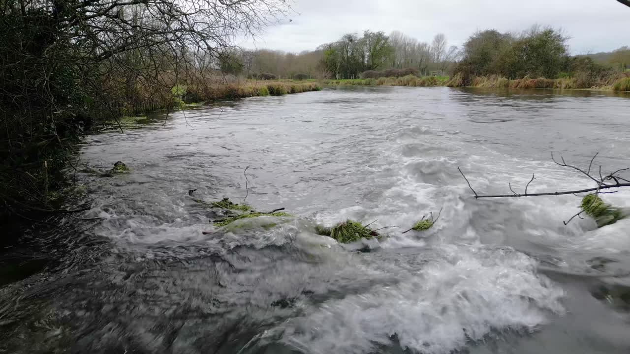 Fast flowing River tumbling over rocks with high water level just short of flood