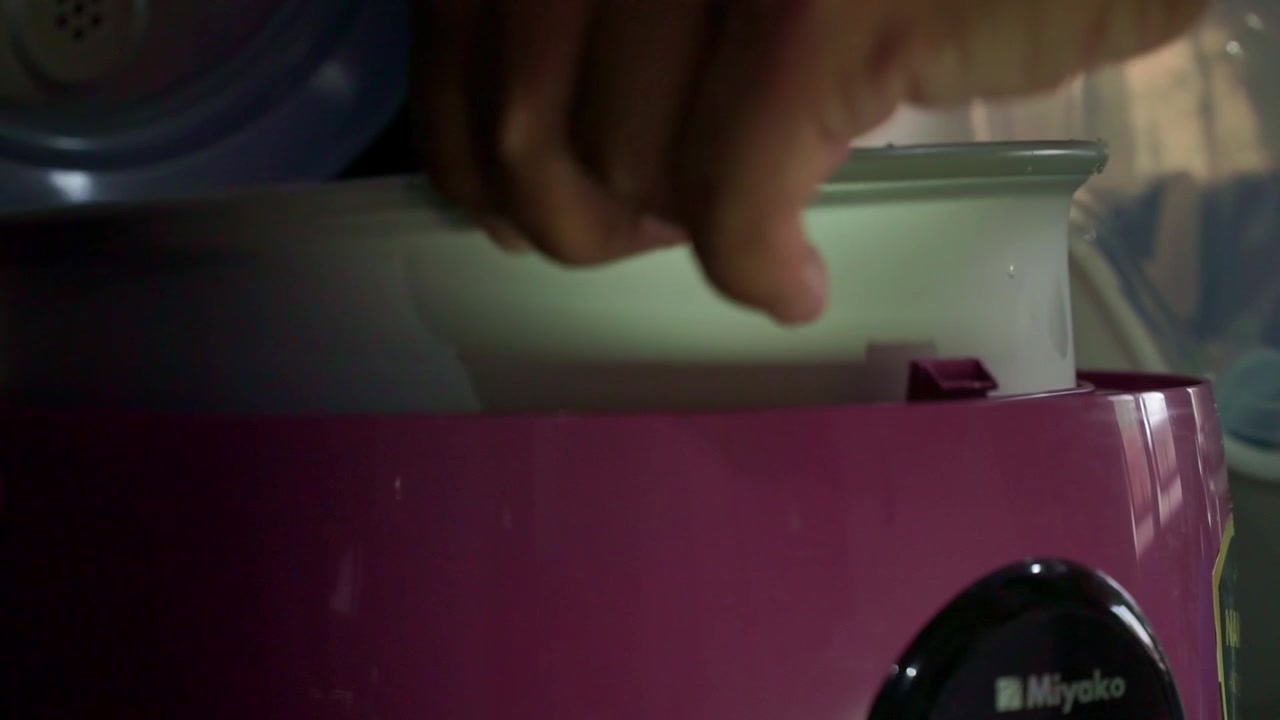 Mano che inserisce una pentola nel cuociriso per iniziare il processo di cottura. Primo piano di un elettrodomestico da cucina, cucina domestica, video stock di preparazione del cibo.