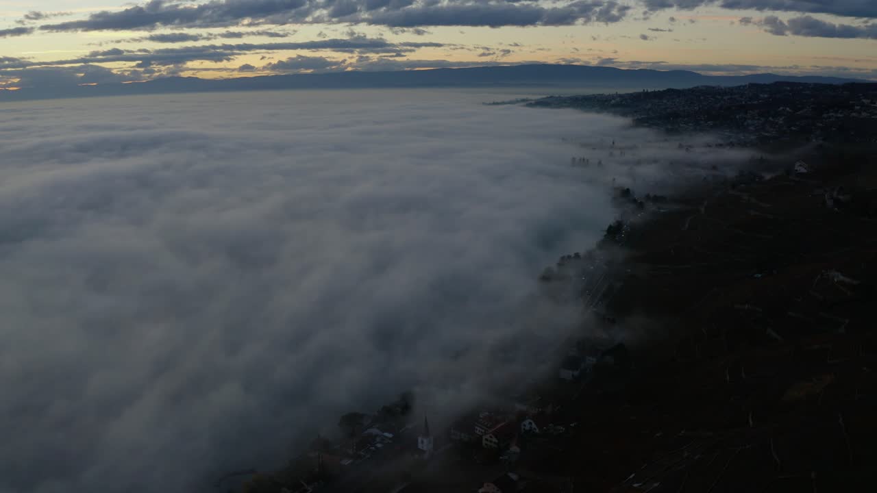 antena volando hacia atrás revelando un mar de niebla sobre el lago léman al atardecer - suiza