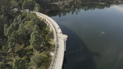 Flug-über-Den-Hollywood-Dam-Mit-Der-Sonne,-Die-Sich-Im-Wasser-Spiegelt,-Und-Der-Skyline-Von-Los-Angeles-Im-Hintergrund