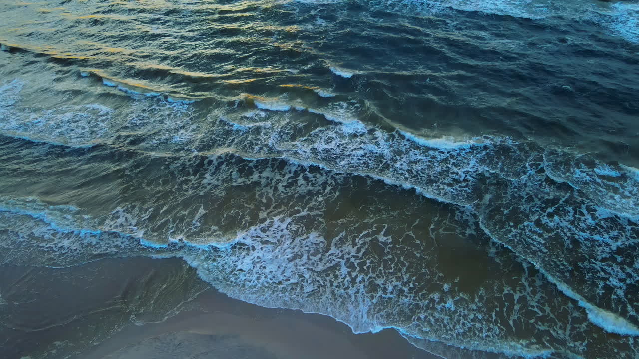 Splendida e calma vista aerea di onde tranquille che si infrangono dolcemente sulla riva di una spiaggia sabbiosa.