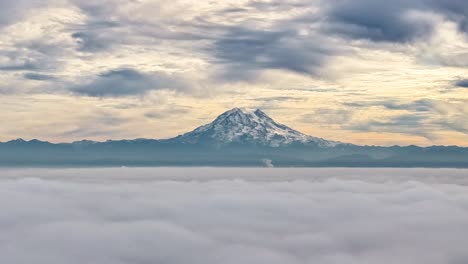 clouds moving above and in front of mount rainier at dusk in washington, usa