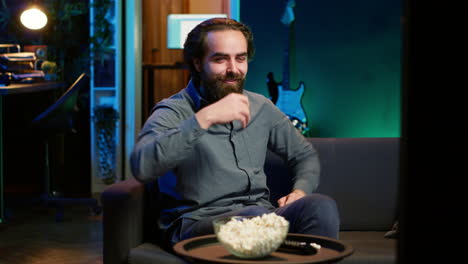 overjoyed man sitting on couch laughing while watching funny comedy movie