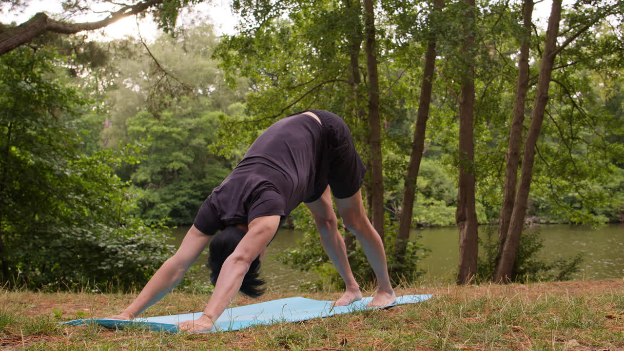 스포츠 옷을 입은 남자가 호수나 강 의 숲에서 마트 위에서 요가를 하고 자연의 평화와 아름다움을 즐기고 있습니다.
