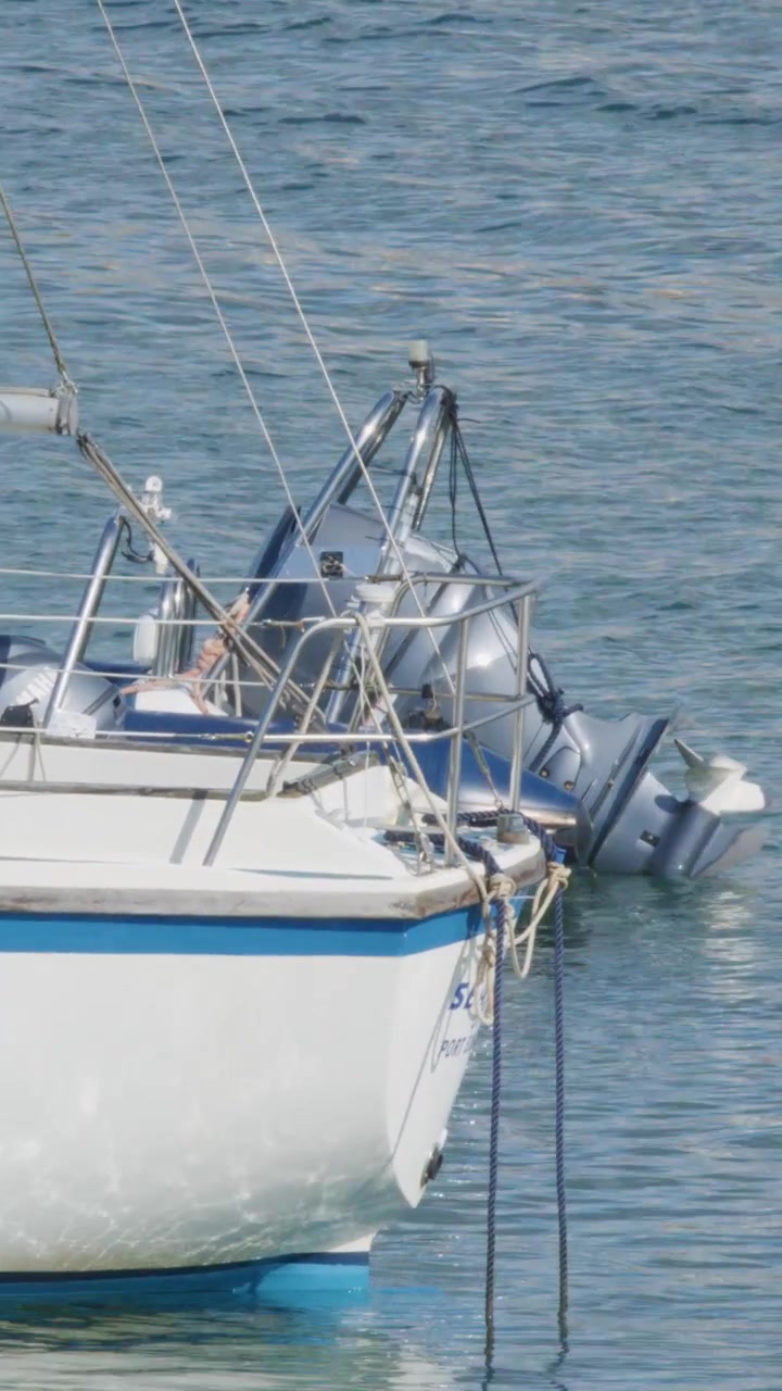 Una barca a vela ferma con un gommone gonfiabile attaccato galleggia su acqua calma a Elie, Fife, Scozia. Piena luce del giorno, movimento minimo della telecamera, atmosfera tranquilla