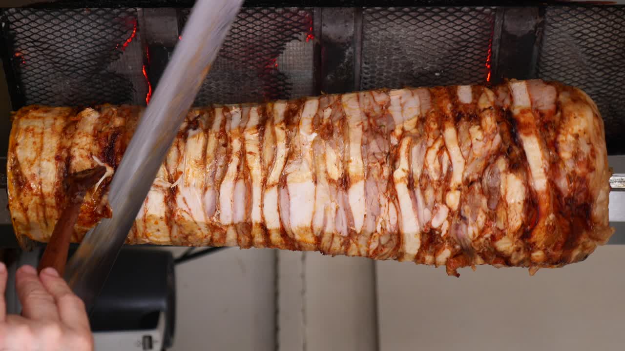 Chef che taglia carne di kebab döner arrosto da una griglia verticale