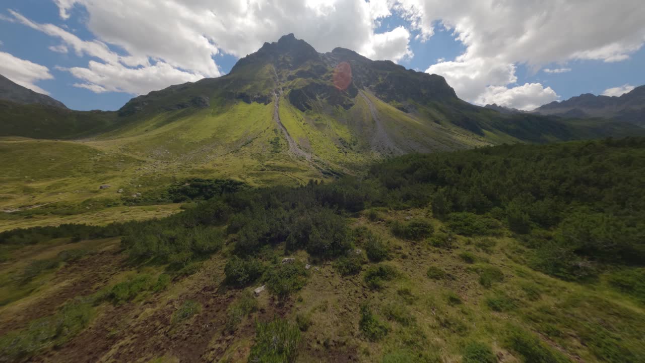 antena fpv rápida que vuela sobre el suelo del valle de silvretta-stausee y sube por un camino de grava a lo largo de la montaña