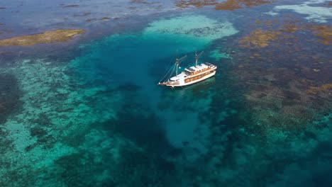 Vista-Aérea-Del-Arrecife-De-Coral-Y-Barco-Turístico-En-Taka-Makassar,-Parque-Nacional-De-Komodo,-Indonesia