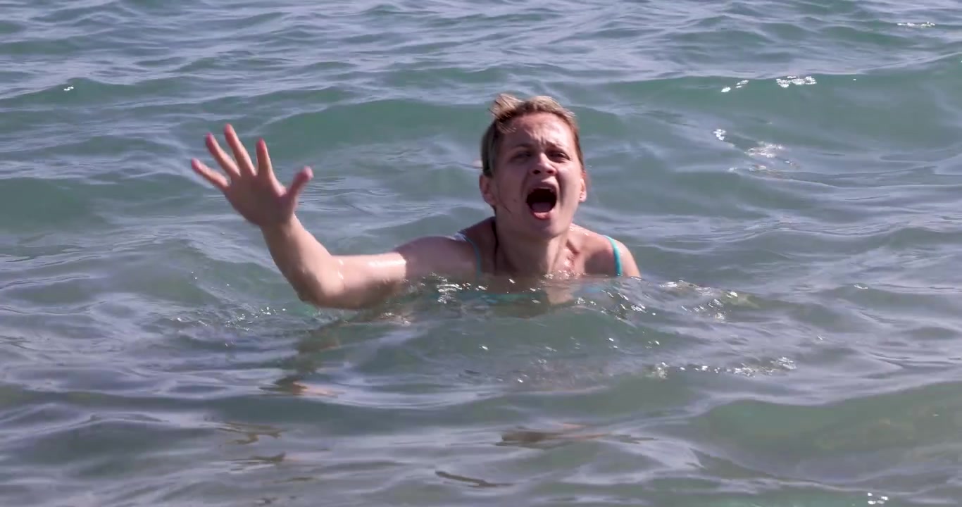 Jovem mulher se afogando gritando e acenando no mar, filme 4k