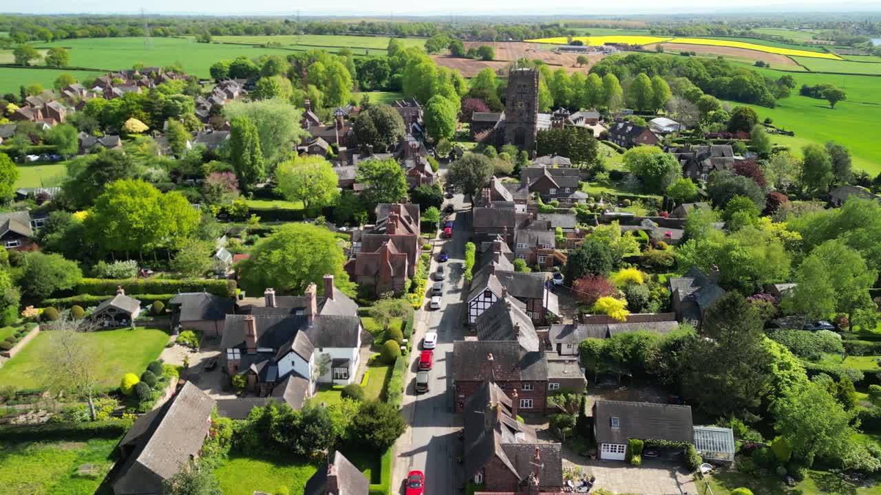 Beautiful St Mary and All Saints Church by drone in the picturesque village of Great Budworth - church approach from village street - Cheshire, UK