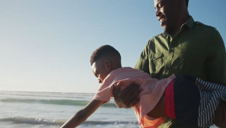 Glücklicher-Afroamerikanischer-Vater,-Der-Mit-Seinem-Sohn-Am-Sonnigen-Strand-Spielt