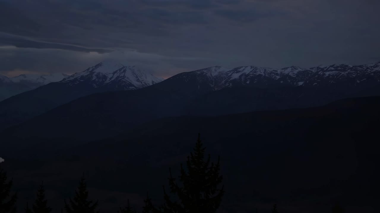 Aerial view of a winding river through mountains at sunset, with dramatic clouds and sun rays