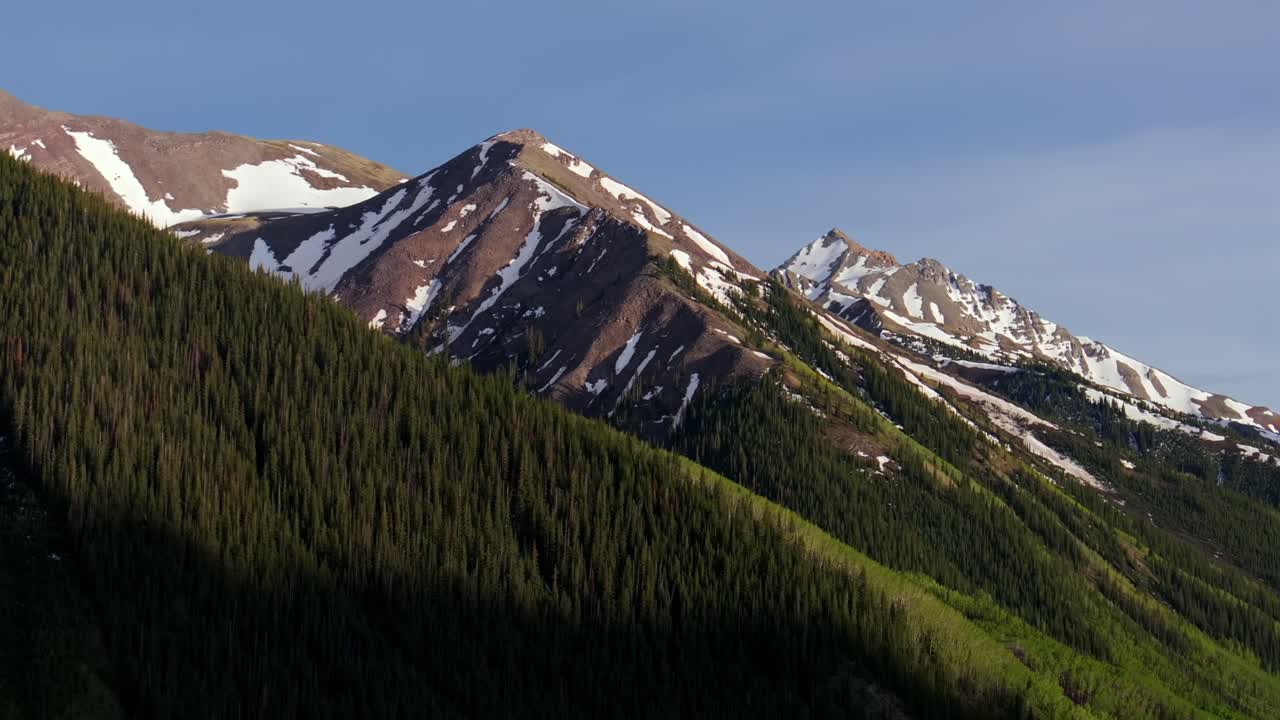Spring summertime Aspen Highlands Bowl ski resort aerial drone Colorado Rocky Mountains Elk Range Mountains Maroon Creek snow fields melting sunset blue sky high clouds parallax circle right