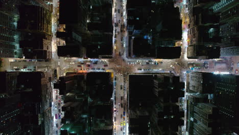 drone top-down view of a hong kong intersection filled with cars and neon-lit buildings at night