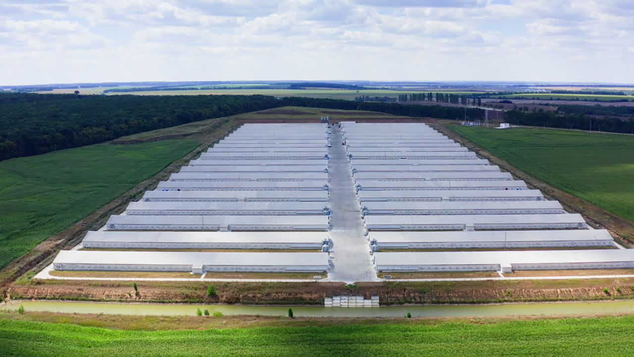 Large modern farm in the countryside. Rows of white farmhouses on field. Agricultural complex on green landscape. Aerial view.