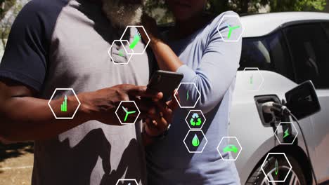 Animation-of-ecology-icons-over-african-american-couple-fueling-car-and-using-smartphone